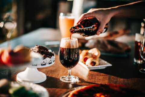 person pouring drink on wine glass